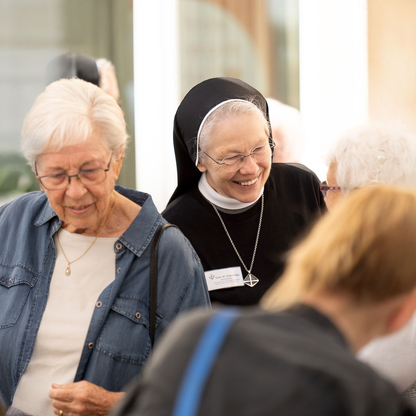 L&auml;chelnde Nonne unterh&auml;lt sich in einer Gruppe von Menschen